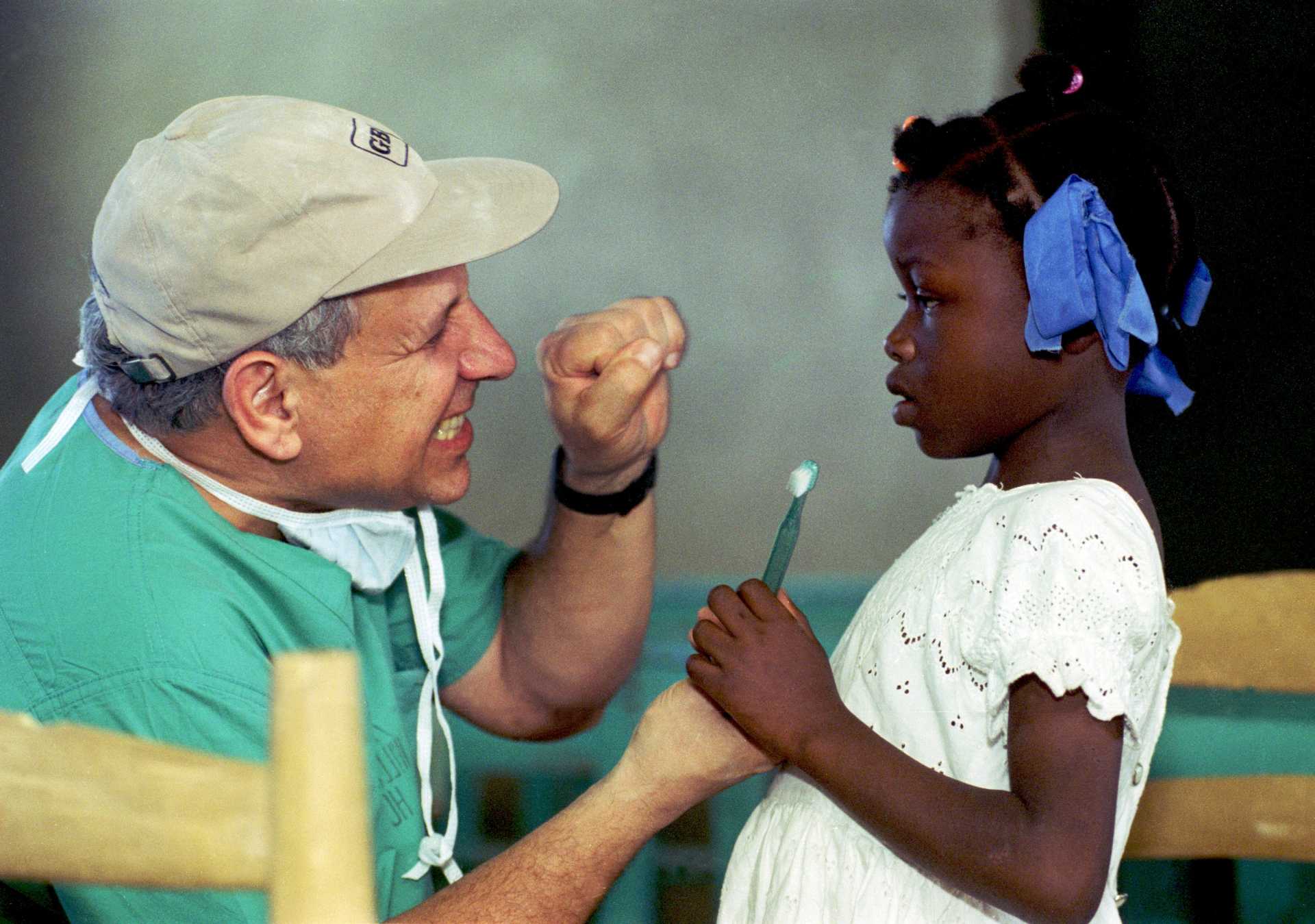 Dr. Nelphison De Almeida of Danbury, Conn., volunteering with the Haitian Health Foundation in Jeremie, Haiti, teaches a Haitian girl to brush her teeth on the island of Haiti.