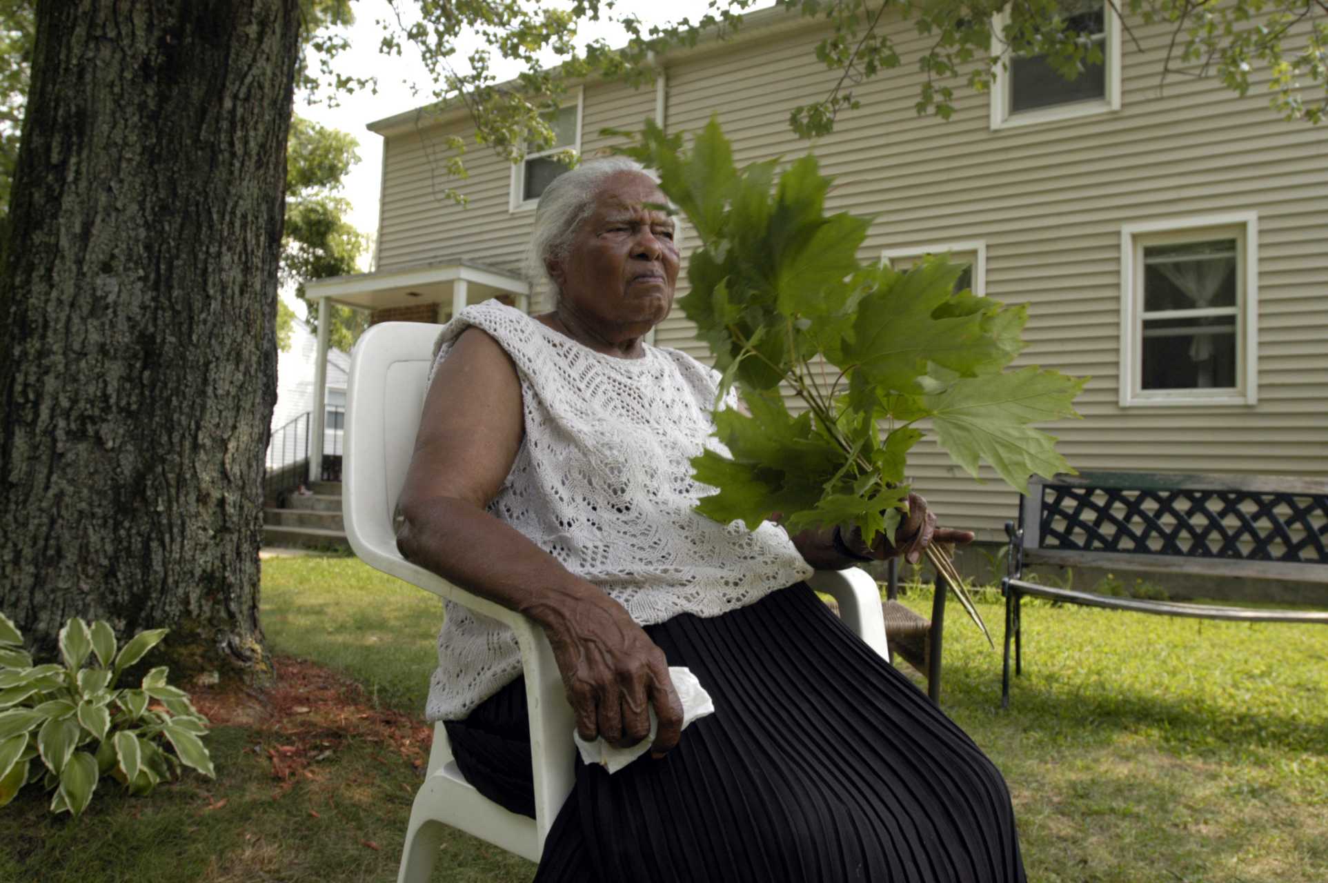 Carmen Ciceron uses a tree branch to cool herself off during a summer afternoon of intense heat.